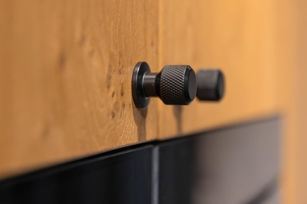 Närbild på svarta, lättrade knoppar på träfärgade skåpsluckor.